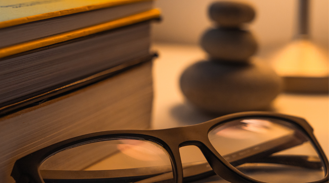 Lunettes de relecture et galets de relaxation posés devant une pile de manuscrits pour la révision professionnelle d'un livre.