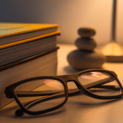 Lunettes de relecture et galets de relaxation posés devant une pile de manuscrits pour la révision professionnelle d'un livre.